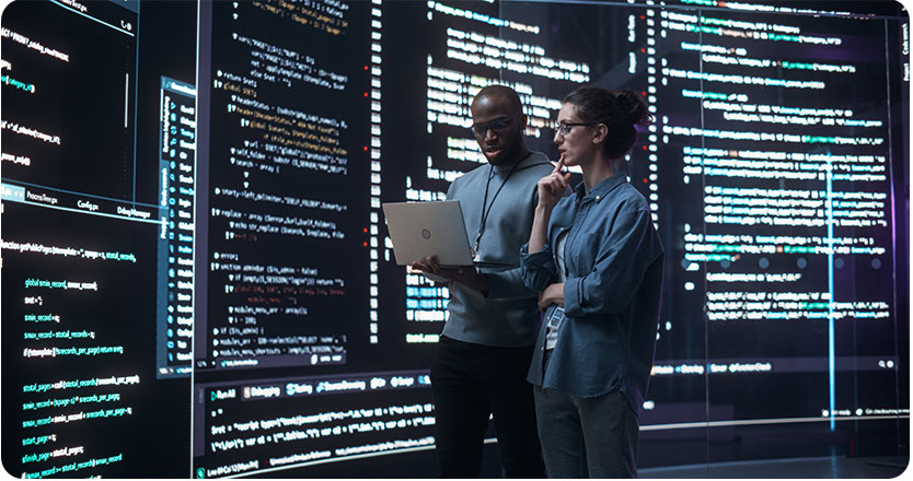 Portrait,Of,Two,Diverse,Developers,Using,Laptop,Computer,,Discussing,Lines Portrait of Two Diverse Developers Using Laptop Computer, Discussing Lines of Code that Appear on Big Screens Surrounding Them. Male and Female Programmers Creating a Software Together, Fixing Bugs